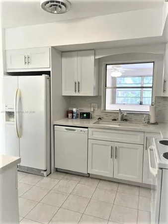 a kitchen with white cabinets and white appliances