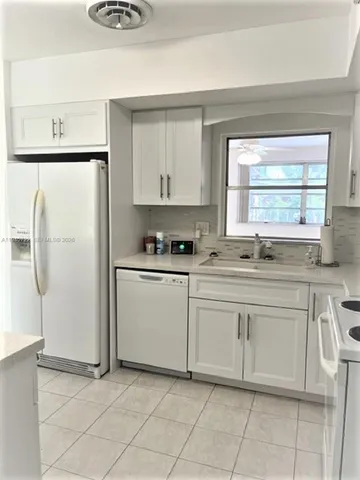 a kitchen with white cabinets and white appliances