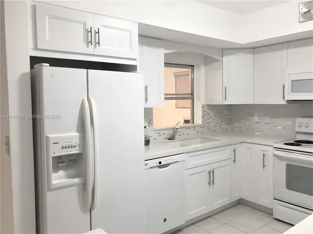 a kitchen with white cabinets and white appliances