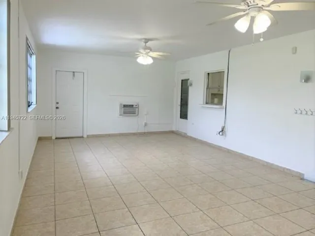 an empty room with a chandelier fan and glass door