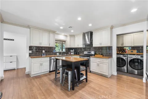 a kitchen with a sink a stove a refrigerator and white cabinets