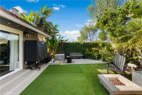 a view of a backyard with table and chairs potted plants and a large tree