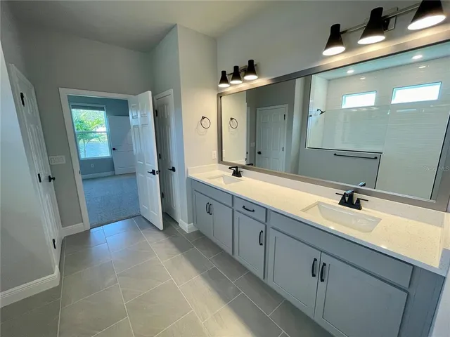 a spacious bathroom with a double vanity sink a mirror and a shower