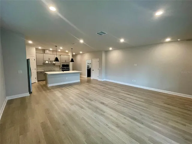 a view of a big room with wooden floor and windows