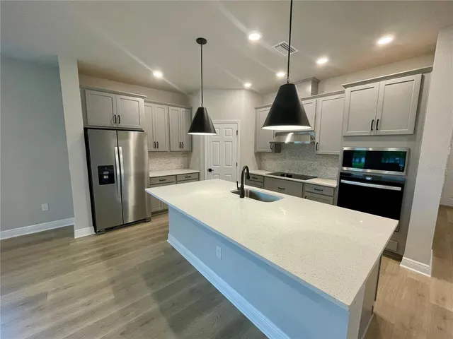 a large kitchen with stainless steel appliances kitchen island a large counter top space a sink a stove a refrigerator and cabinets