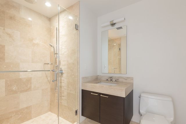a bathroom with a granite countertop sink mirror and a shower