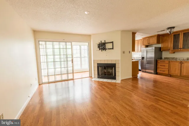 a view of a livingroom with a fireplace a ceiling fan and wooden floor
