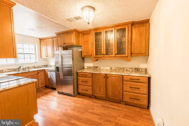 a kitchen with stainless steel appliances granite countertop a refrigerator a stove and a sink with cabinets