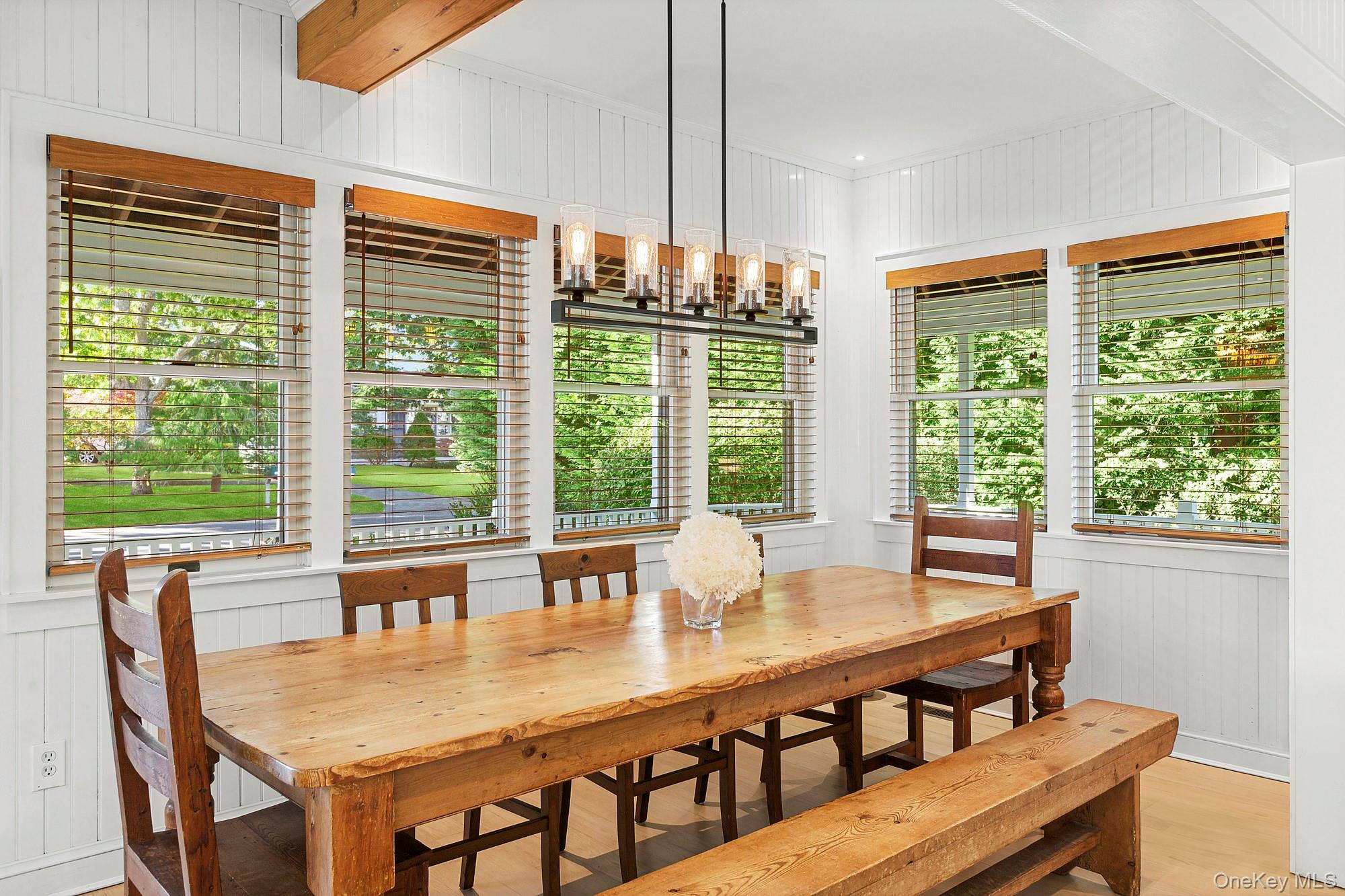21 Cove Road Sag Harbor, NY 11963 - Photo 11 of 37 Dining area with wood walls, a chandelier, light wood-style floors, and a decorative wall