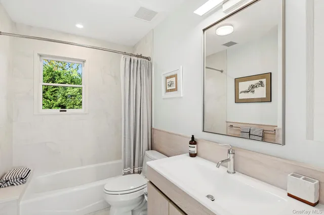 a bathroom with a bathtub shower sink vanity mirror and toilet