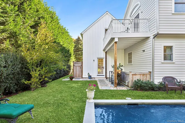 a view of a white house next to a yard with big trees
