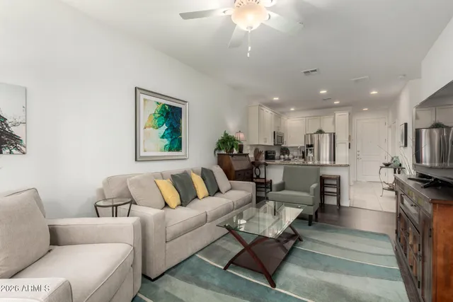 a living room with furniture kitchen view and a chandelier