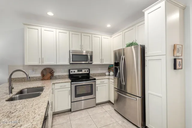 a kitchen with stainless steel appliances granite countertop a refrigerator sink and stove