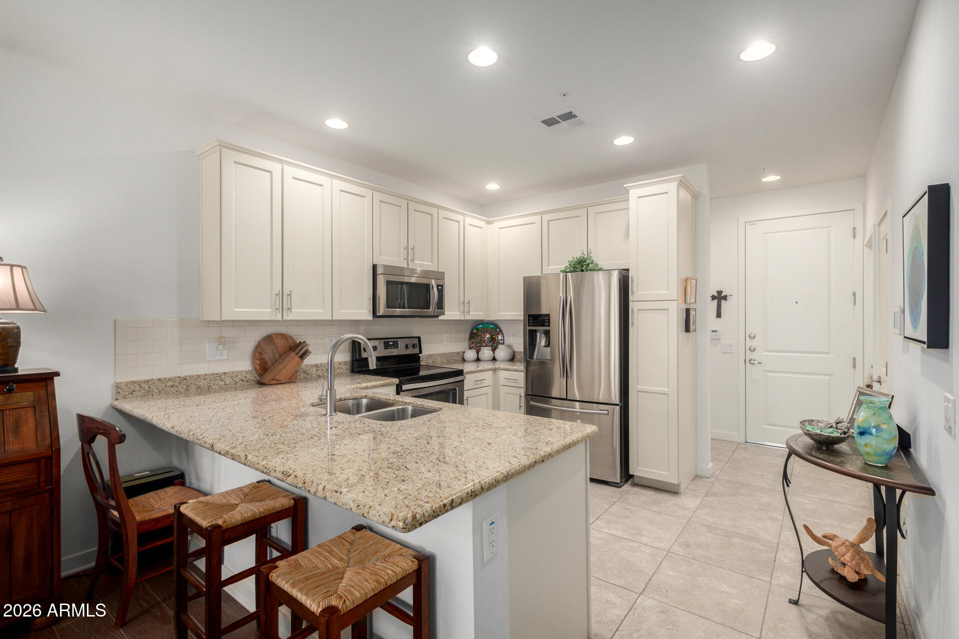 2511 West Queen Creek Road, Unit 124 Chandler, AZ 85248 - Photo 8 of 39 a kitchen with kitchen island granite countertop a table chairs refrigerator and microwave