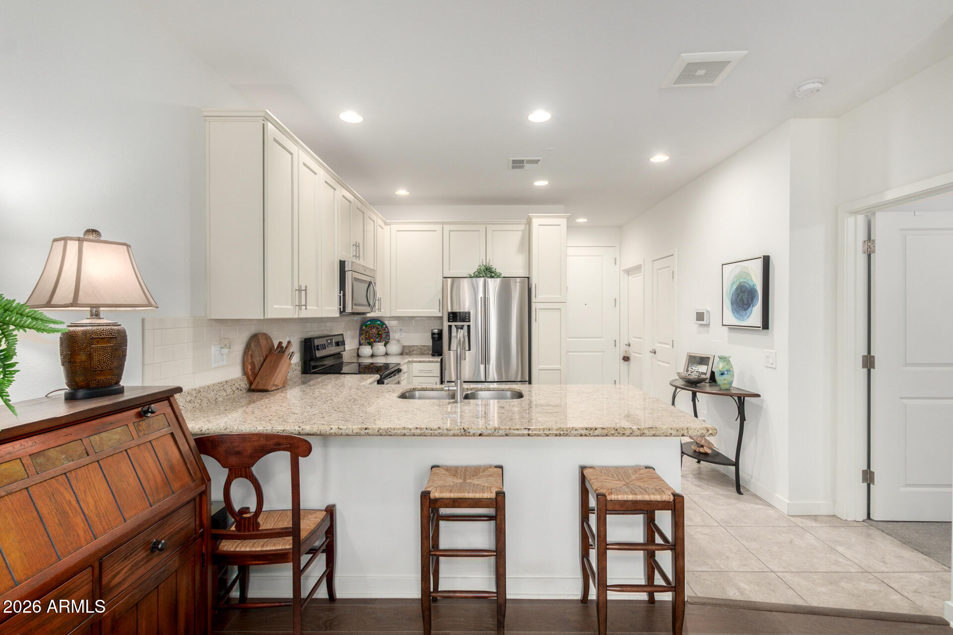 2511 West Queen Creek Road, Unit 124 Chandler, AZ 85248 - Photo 9 of 39 a kitchen with kitchen island granite countertop a dining table chairs refrigerator and cabinets