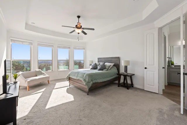 a spacious bedroom with a bed a couch and a large window