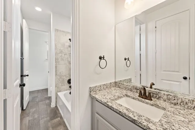 a bathroom with a granite countertop sink a mirror and shower