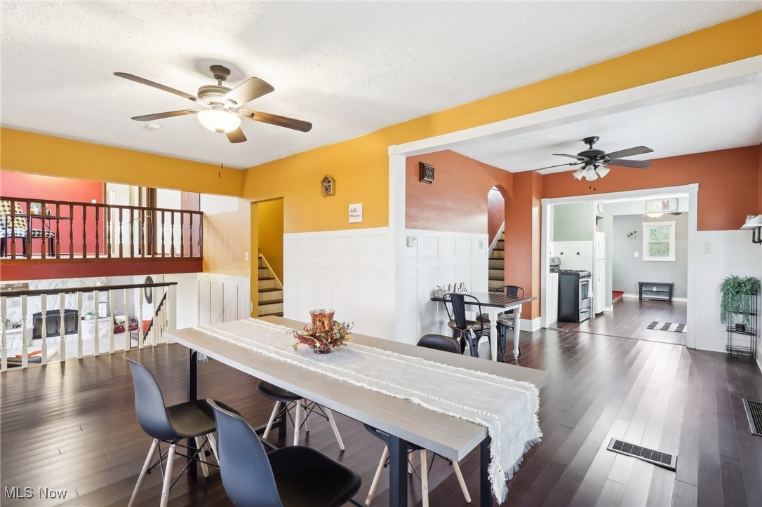 22120 Center Road Alliance, OH 44601 - Photo 20 of 41 Dining space featuring a ceiling fan, stairway, arched walkways, wood finished floors, and a wainscoted wall