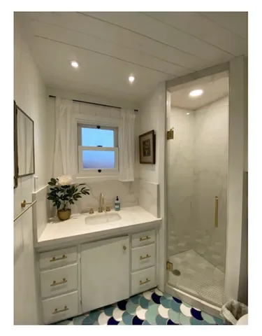 a bathroom with a sink mirror and shower