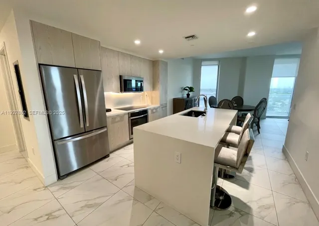 a kitchen with refrigerator and chairs