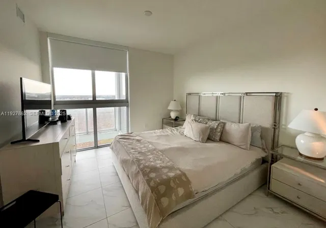 a spacious bedroom with a bed a table and flat screen tv