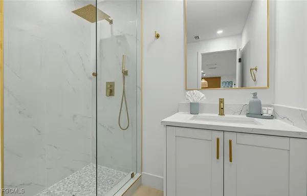 a bathroom with a granite countertop sink a mirror and shower