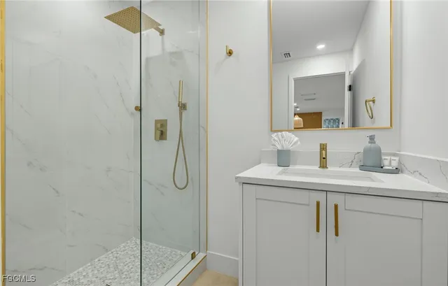 a bathroom with a granite countertop sink a mirror and shower