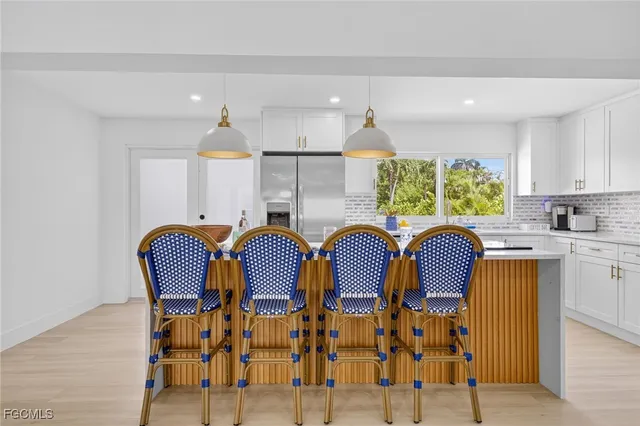 a kitchen with stainless steel appliances granite countertop a table chairs and a refrigerator