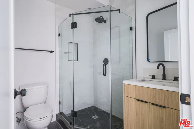 a bathroom with a granite countertop sink a toilet and shower