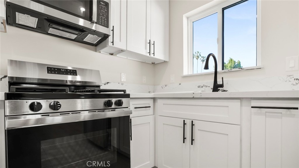 19928 Hatton Street Winnetka, CA 91306 - Photo 5 of 15 a kitchen with stainless steel appliances white cabinets and a sink