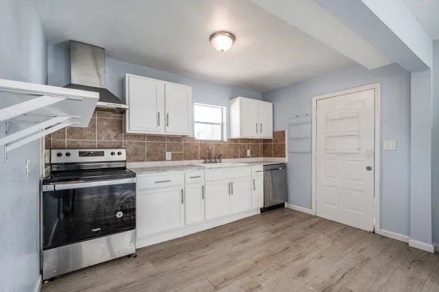 a kitchen with granite countertop white cabinets and stainless steel appliances