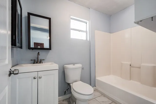 a bathroom with a toilet a sink a mirror and vanity