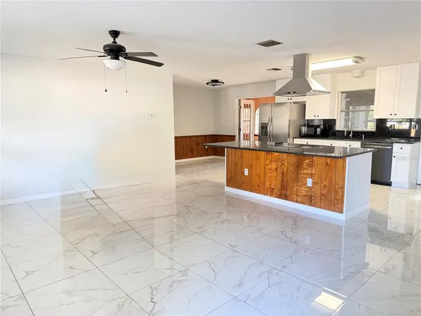 a view of a kitchen with kitchen island a sink stainless steel appliances and cabinets
