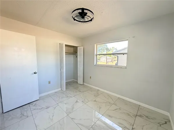 an empty room with windows and ceiling fan