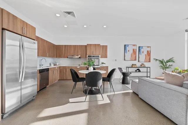 a living room with stainless steel appliances kitchen island granite countertop furniture and a refrigerator