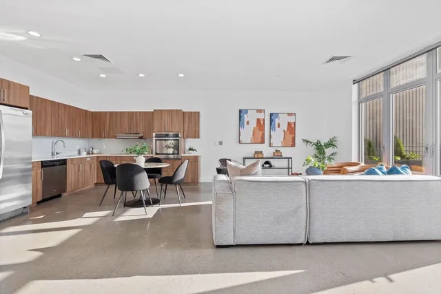 a living room with stainless steel appliances kitchen island a table chairs and a living room view