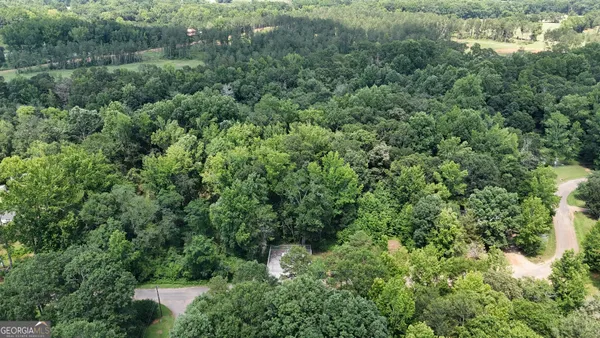 an aerial view of residential house with outdoor space and trees all around
