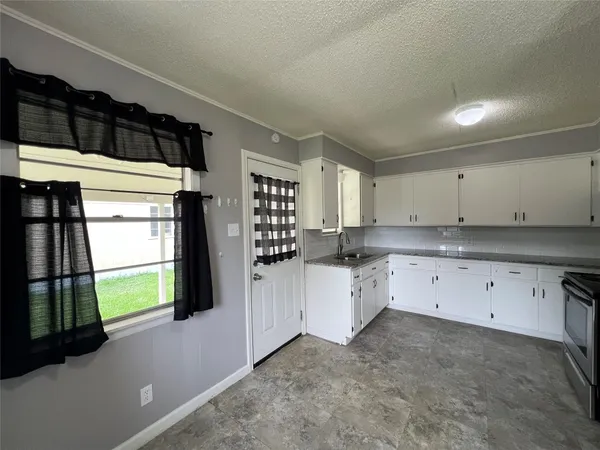a kitchen with white cabinets and window