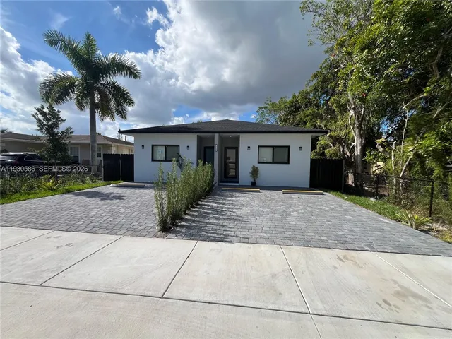 front view of house with potted plants and palm trees