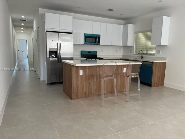 a kitchen with stainless steel appliances granite countertop a stove top oven a refrigerator a sink and a granite counter tops