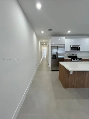 a large kitchen with a large counter top a stove a refrigerator and cabinets