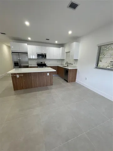 a large kitchen with stainless steel appliances a large counter top