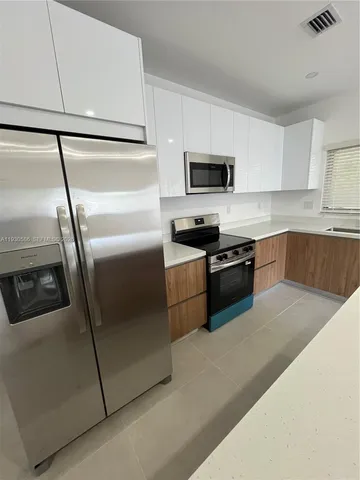 a kitchen with stainless steel appliances a refrigerator a sink a stove top oven a counter space and cabinets