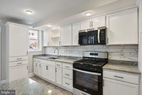 a kitchen with stainless steel appliances granite countertop white cabinets granite counter tops and a window