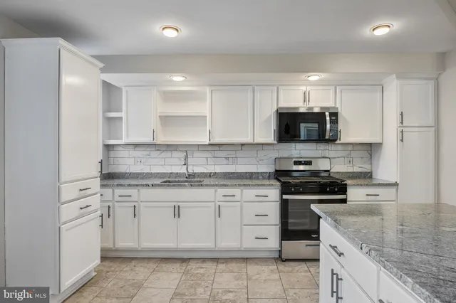 a kitchen with granite countertop white cabinets and stainless steel appliances