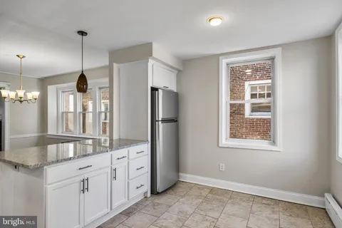 a large kitchen with granite countertop a refrigerator a sink and dishwasher