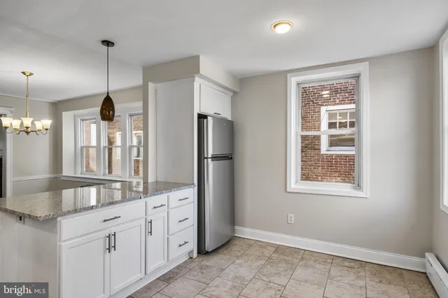 a large kitchen with granite countertop a refrigerator a sink and dishwasher