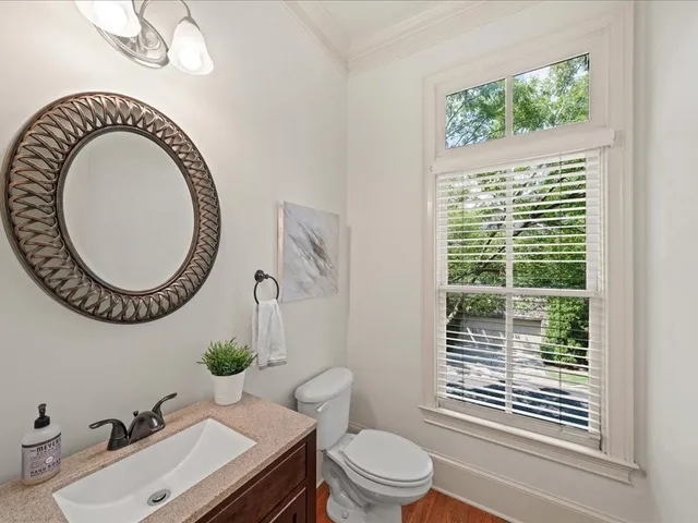 a bathroom with a sink a mirror a toilet and a window