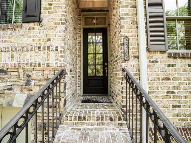 a view of a brick building next to a yard with potted plants