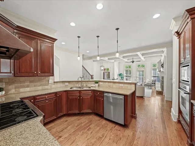 a kitchen with stainless steel appliances granite countertop a sink a stove and a wooden floors